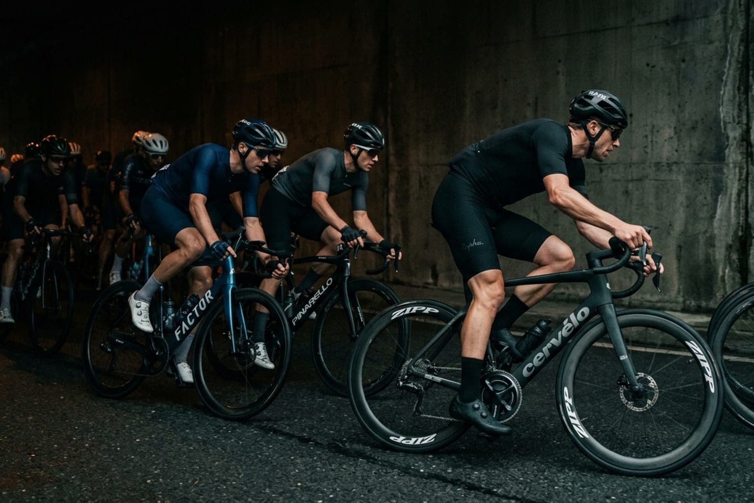 Cyclists riding in a tight indoor tunnel peloton with an outside rider accelerating to move past boxed-in wheels ahead.